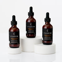 Three Esarchi liquid dropper bottles on white pedestals with a white background